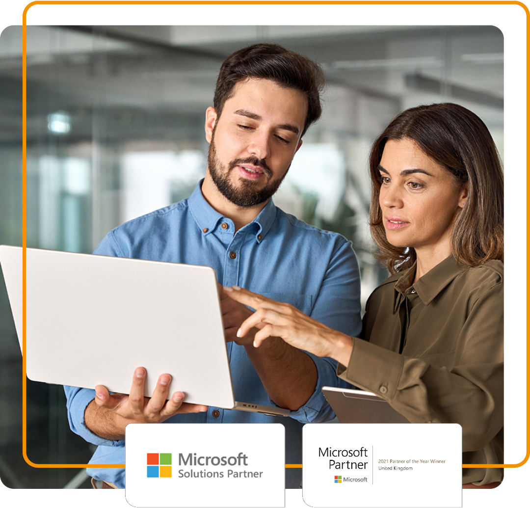 Image of two colleagues stood with a laptop in an office environment with our Microsoft Solution Partner and Microsoft 2021 UK Partner of the Year logos