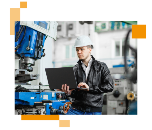 Image of a car mechanic stood in a factor holding a laptop