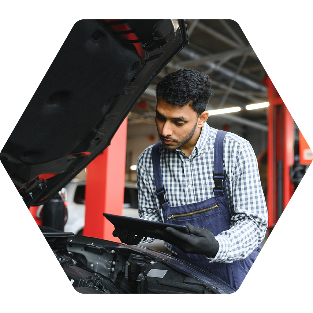 Image of a car mechanic working on a car and holding a tablet