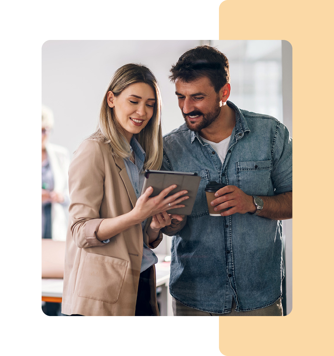 Image of two colleagues conversing and working on a tablet