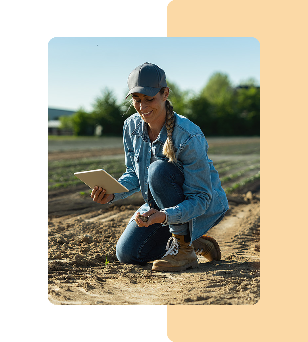 Image of a farmer kneeling in a field holding a tablet