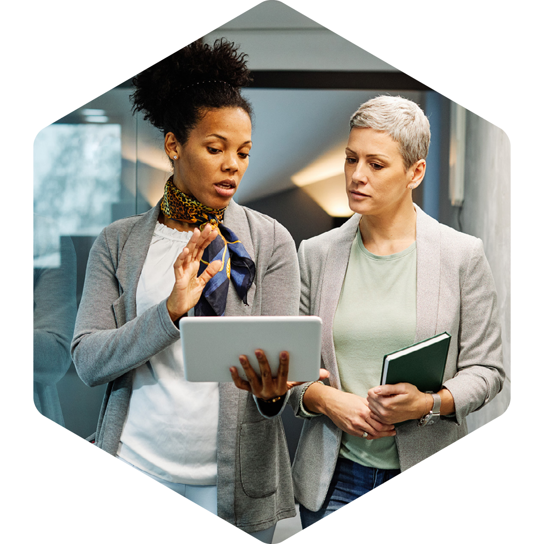 Image of two business professionals walking in an office looking at a tablet