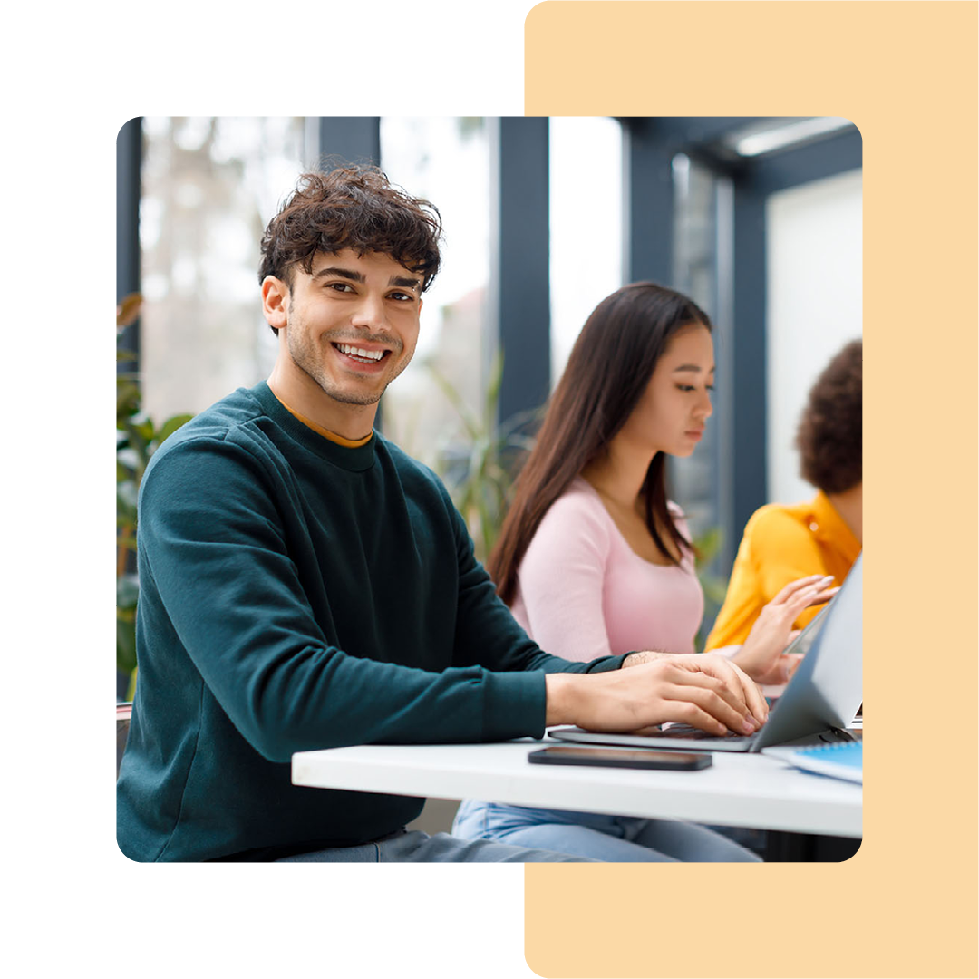 Image of a group of students sat in a room working on laptops