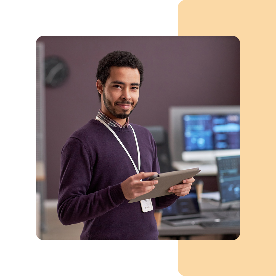 Image of an IT professional stood in a office holding a tablet