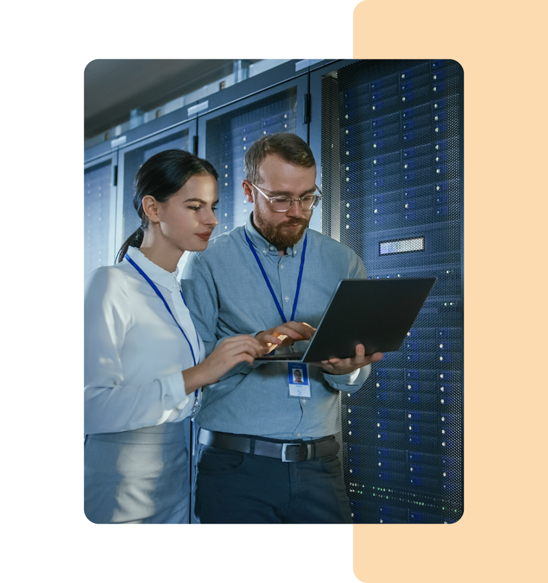 Image of two IT professionals holding a laptop in a data storage room