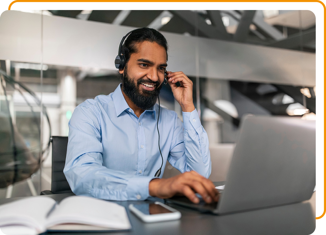 Image of an IT support professional talking on a headset working on a laptop