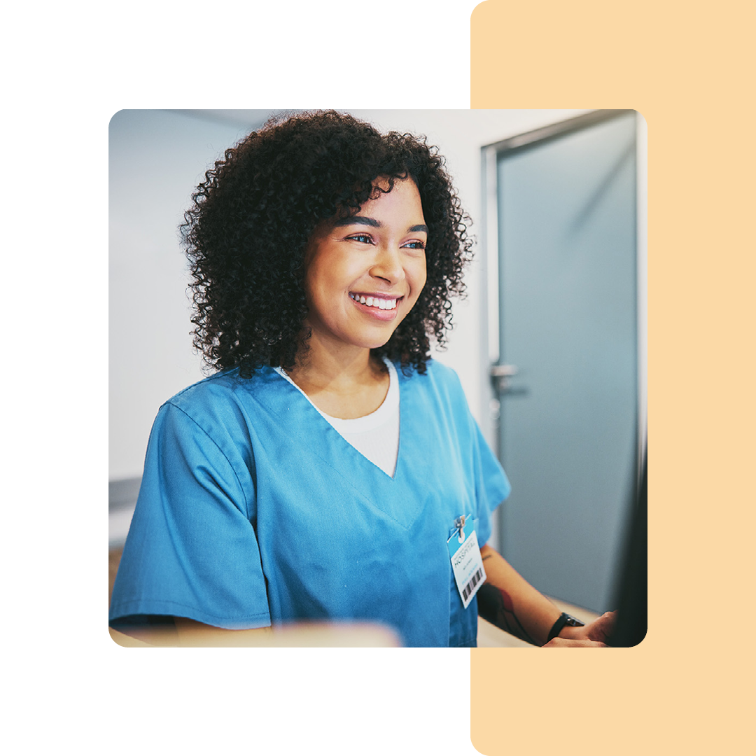 Image of a smiling doctor sat working on a computer