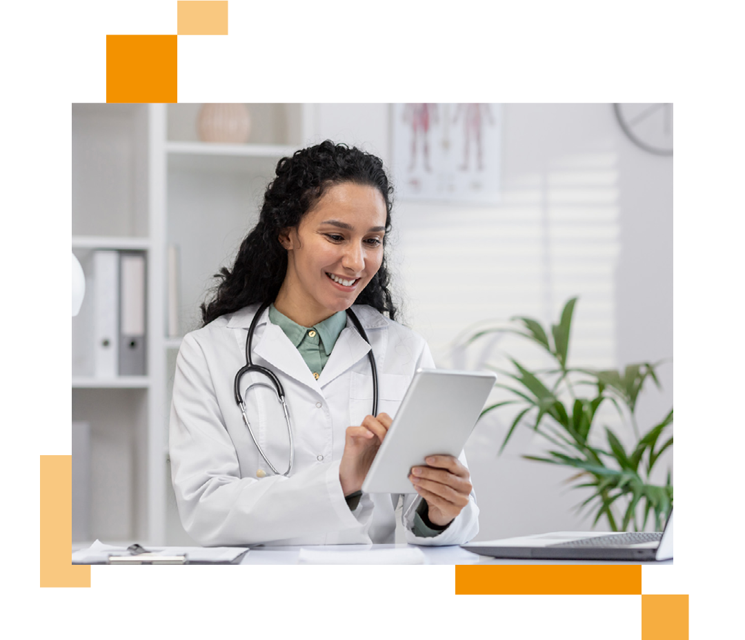 Image of a smiling doctor sat at a desk working on a tablet