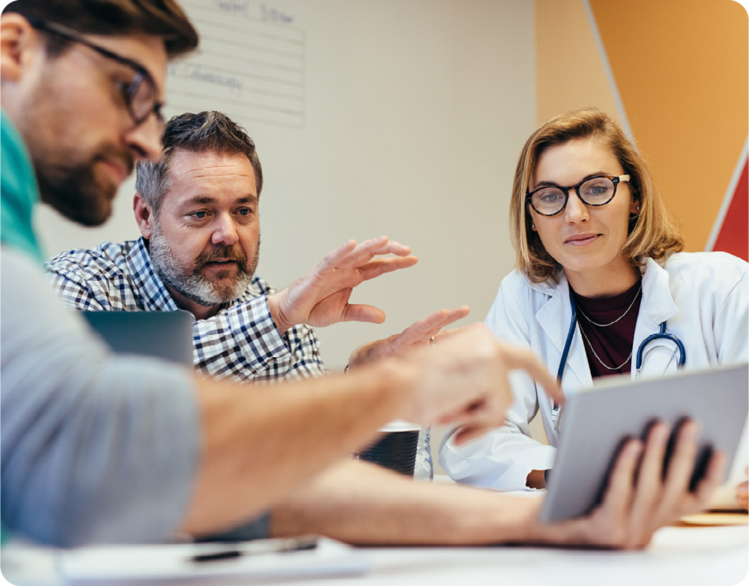 Image of a group of doctors in a meeting talking about information on a tablet