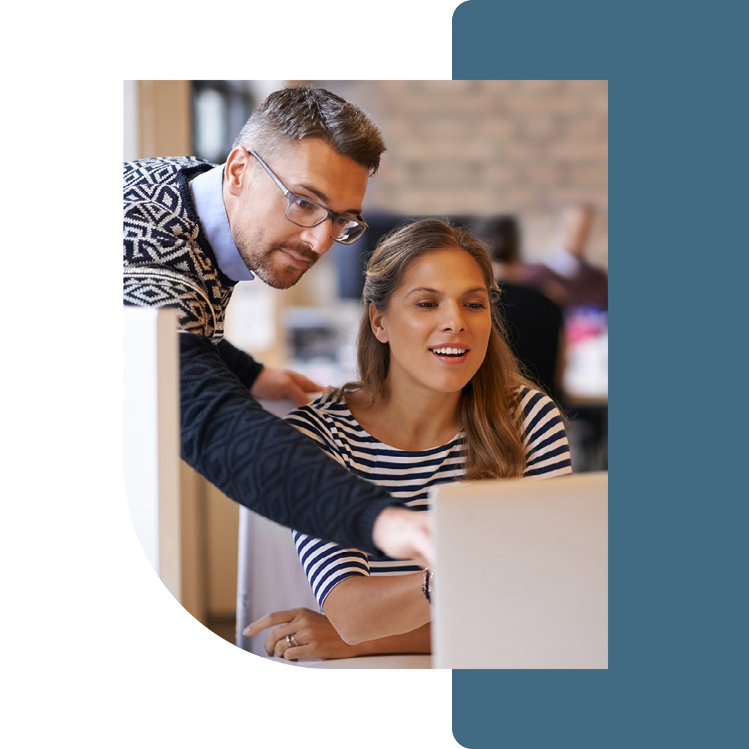 Image of a person helping a colleague working on a laptop