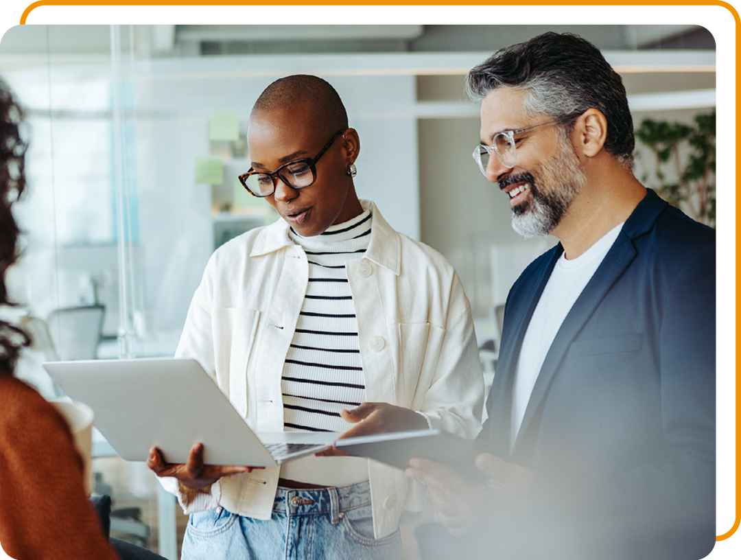 Image of two business professionals stood working on a laptop