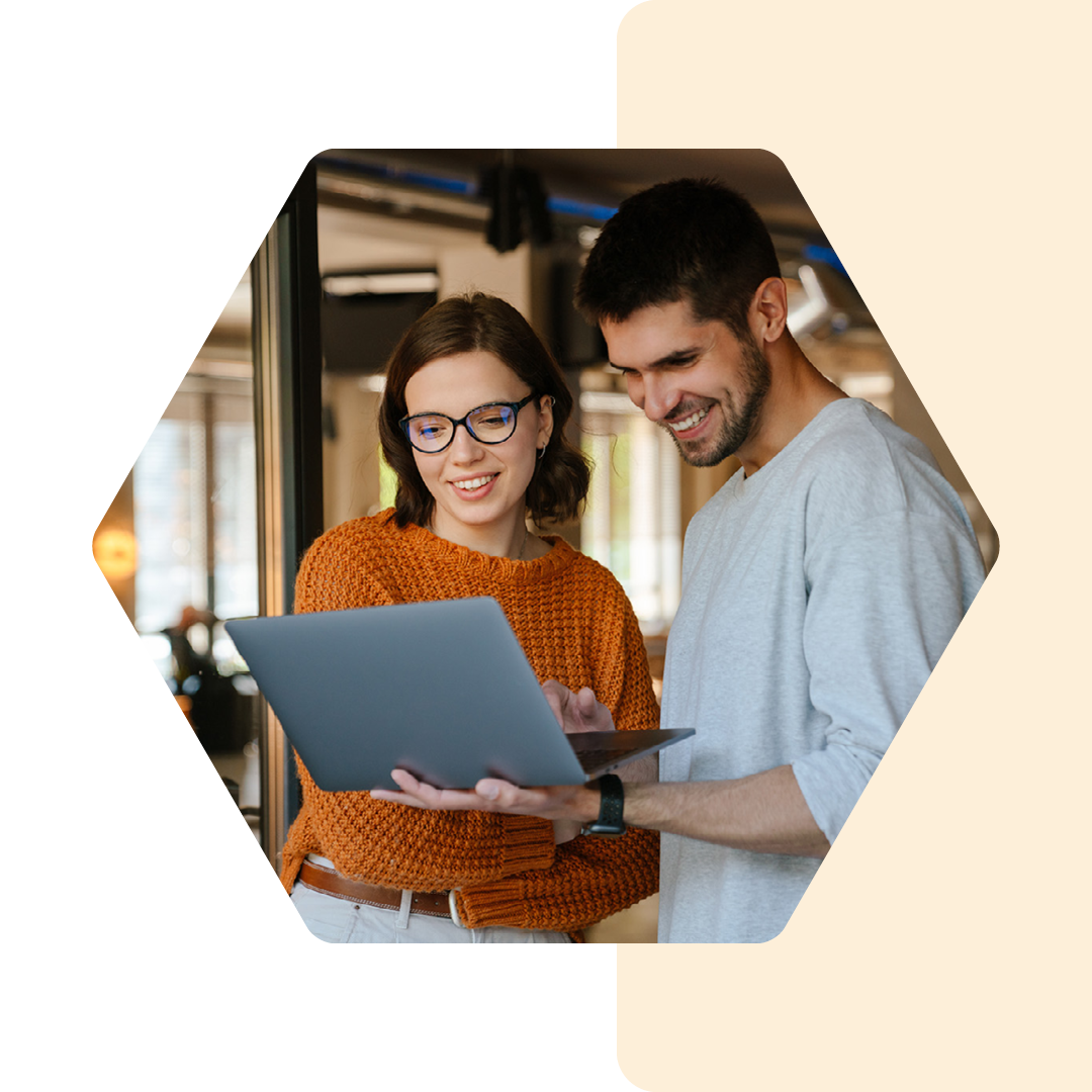 Image of two people talking and working on a laptop