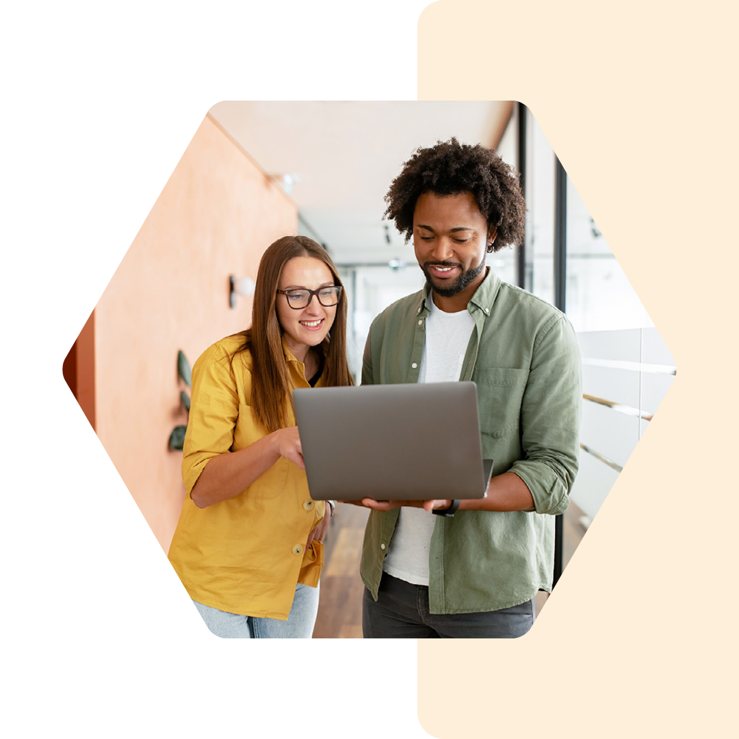 Image of two people standing talking with a laptop