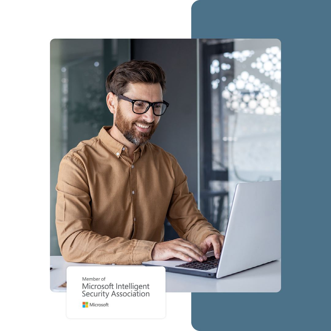 Image of a smiling IT professional working on a laptop with our Microsoft Intelligent Security Association logo