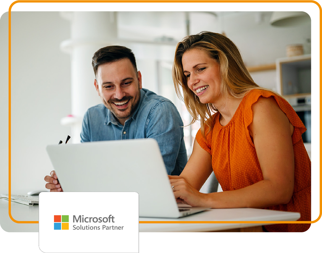 Image of two people sat in an office working on a laptop with Phoenix's Microsoft Solutions Partner logo