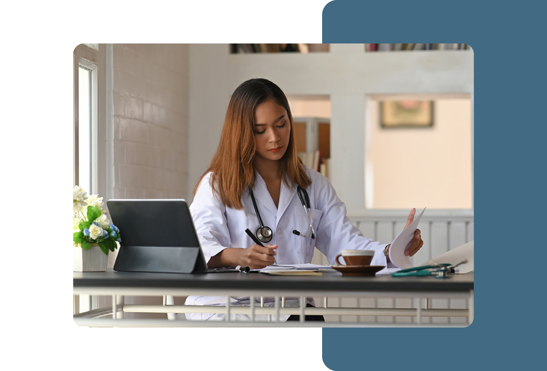 Image of a doctor working at a desk writing in a notepad