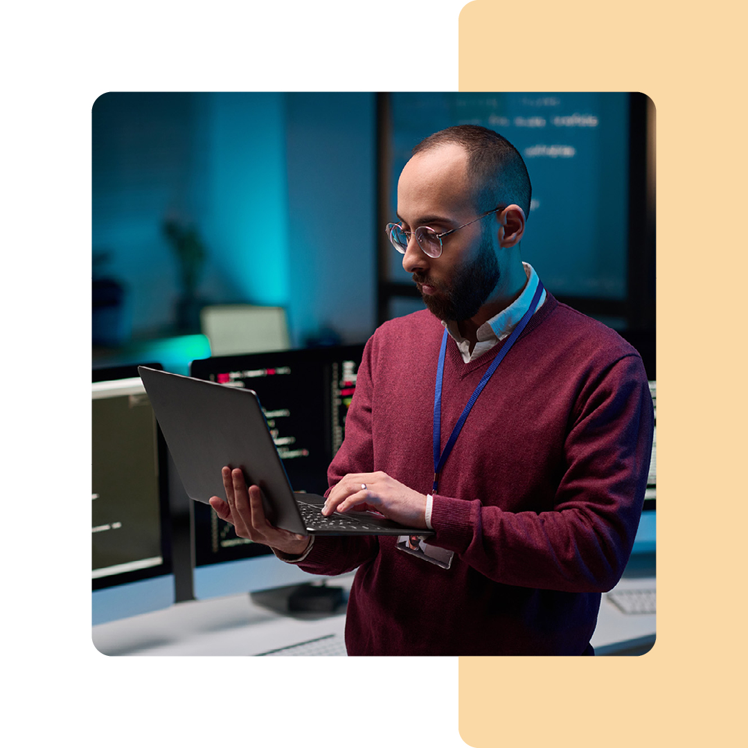 Image of an IT professional stood working on a laptop