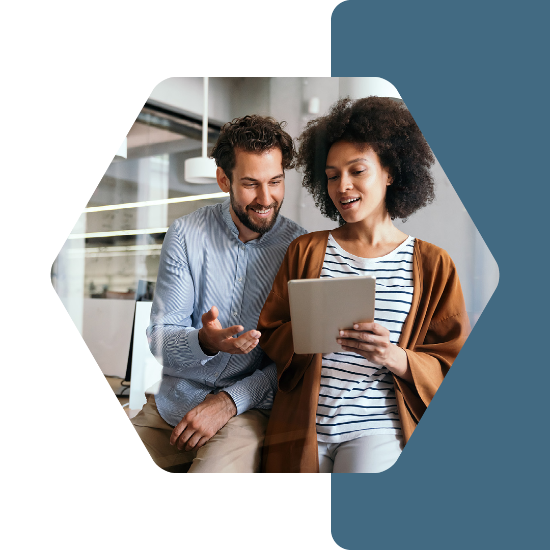 Image of two colleagues talking and working on a tablet together