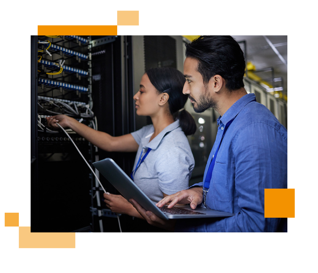 Image of two IT professionals stood in a server room holding a laptop