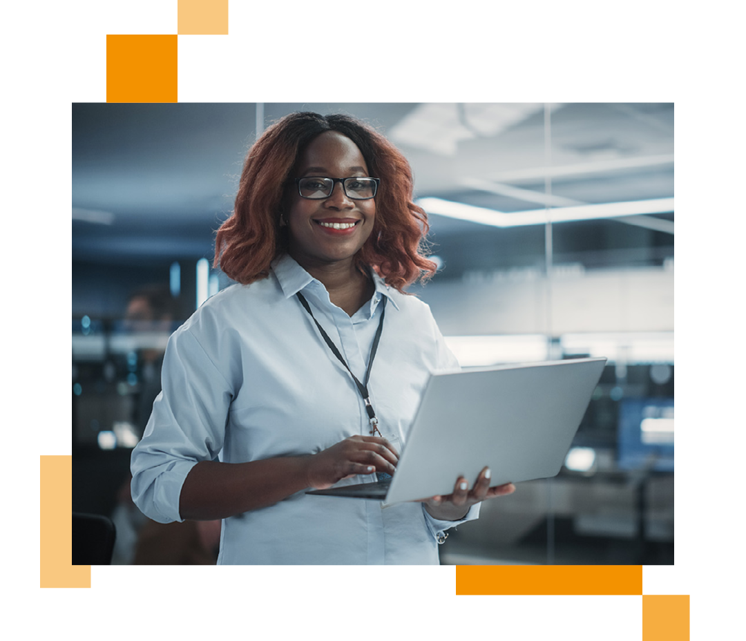 Image of a smiling IT professional stood in a server room holding a laptop