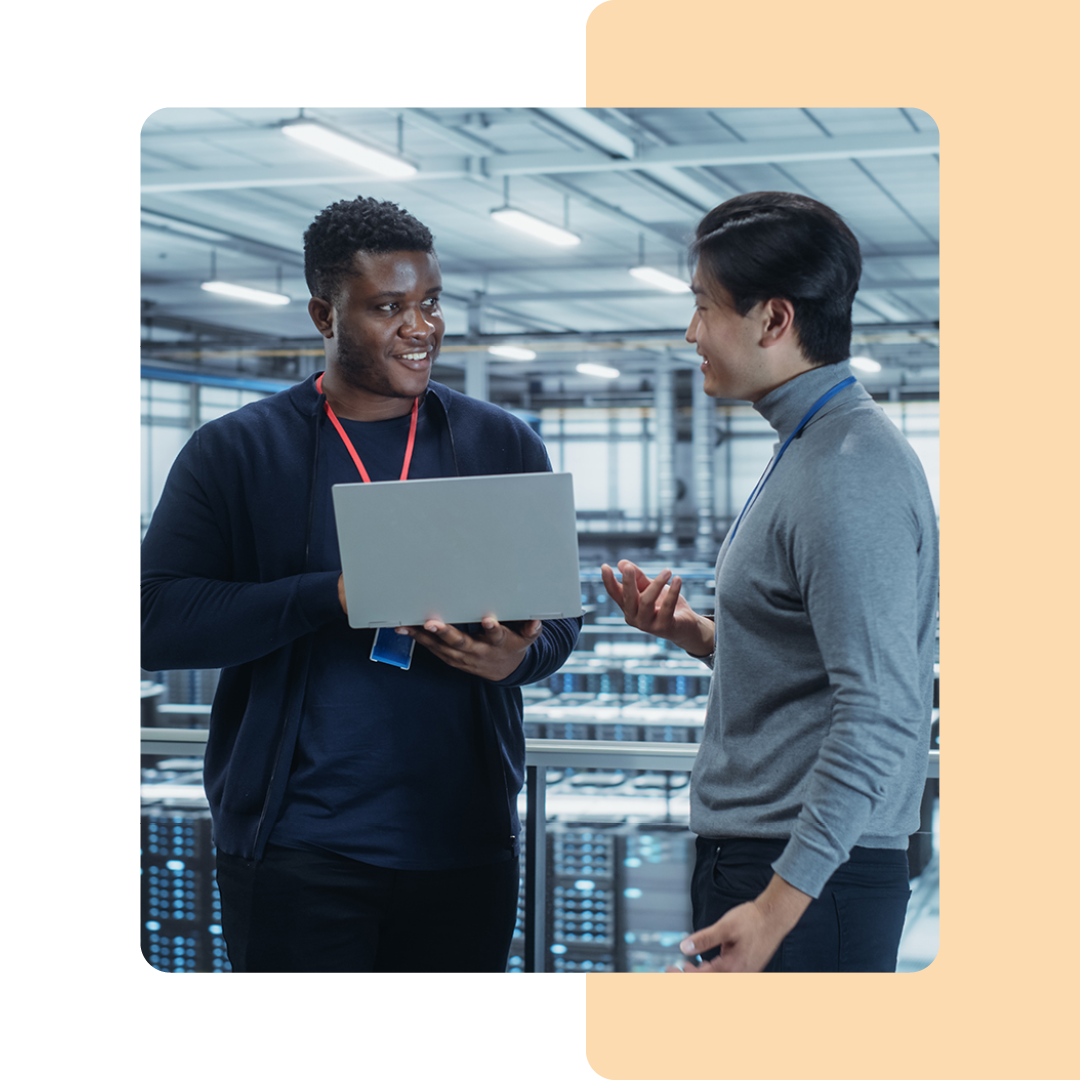 Image of two IT professionals working on a laptop in a server room