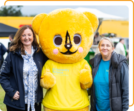 Image of two Phoenix Software employees with the St Leonards Hospice mascot at a Community Event