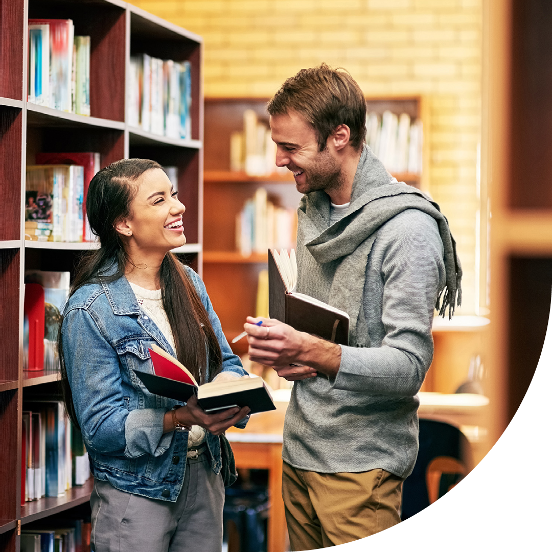 Image of two university students conversing in a library