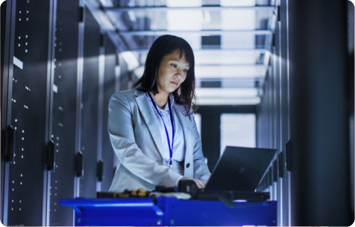 business woman in suit working at a laptop in a dark server room