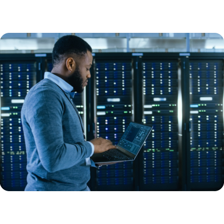 man with laptop walking past servers in server room