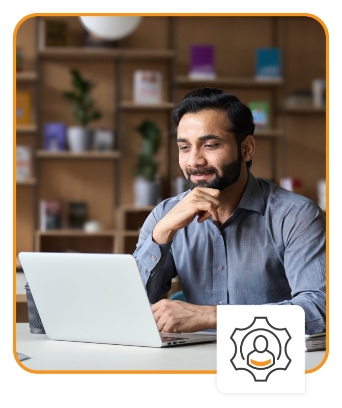 Smiling businessman working on laptop in modern office lobby space.