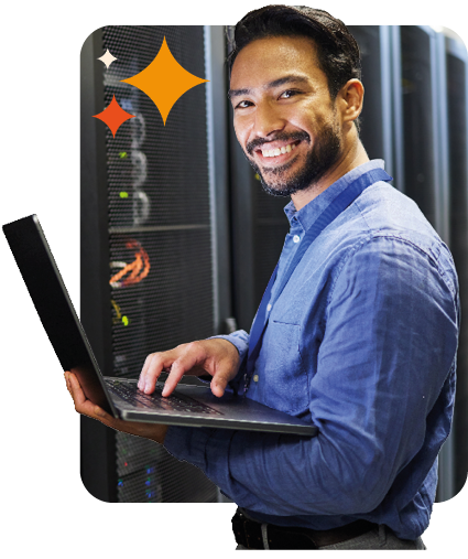 man smiling with laptop in server room